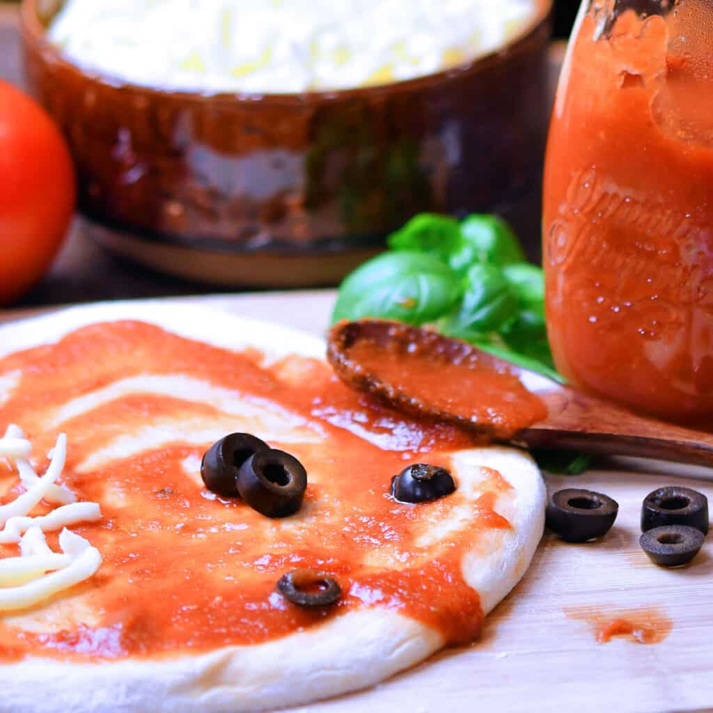 fresh pizza dough, lightly sauced on a cutting board