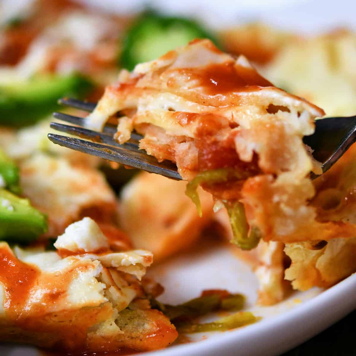 Closeup of sour cream enchiladas cut into pieces on a fork