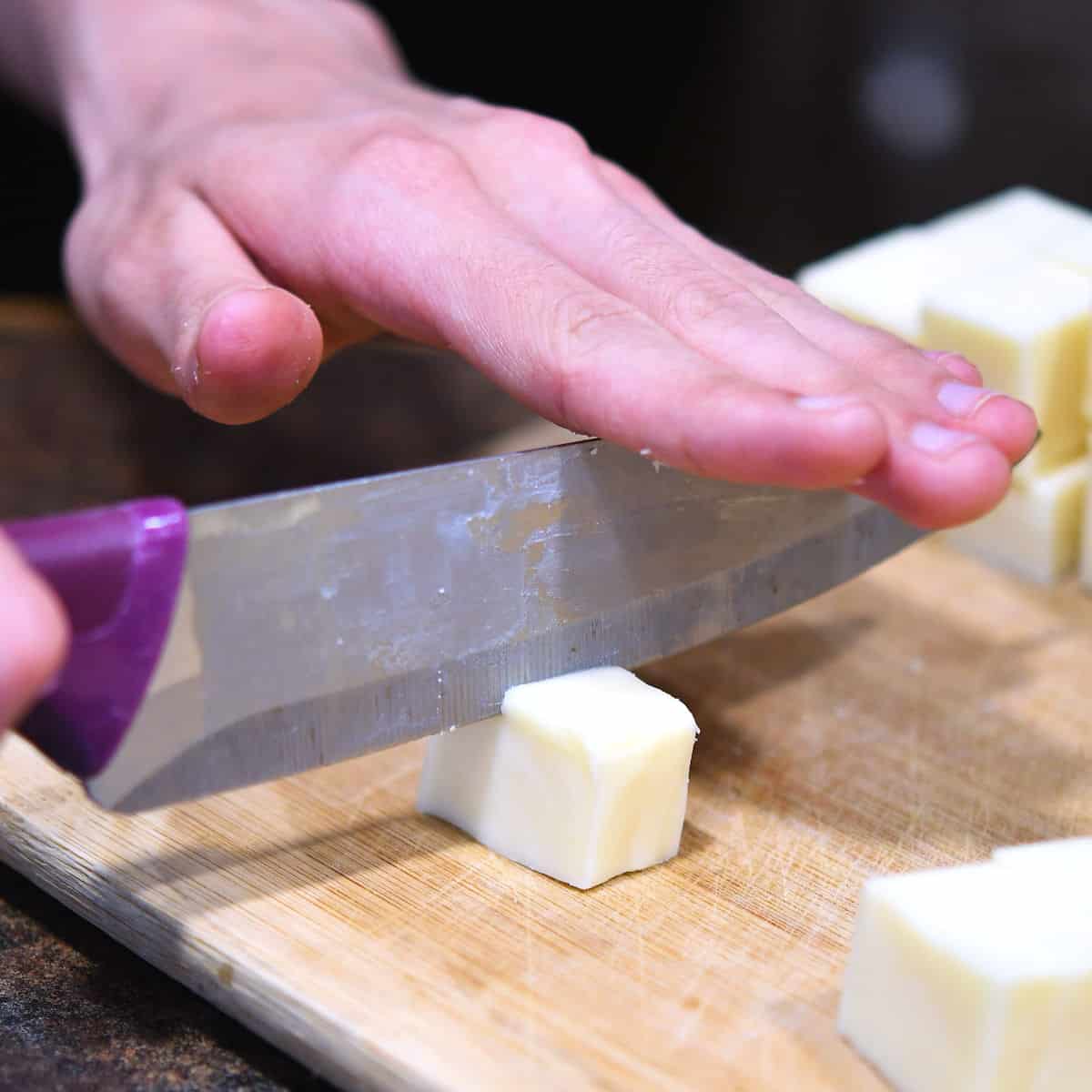 closeup of cutting white cheese on a cutting board
