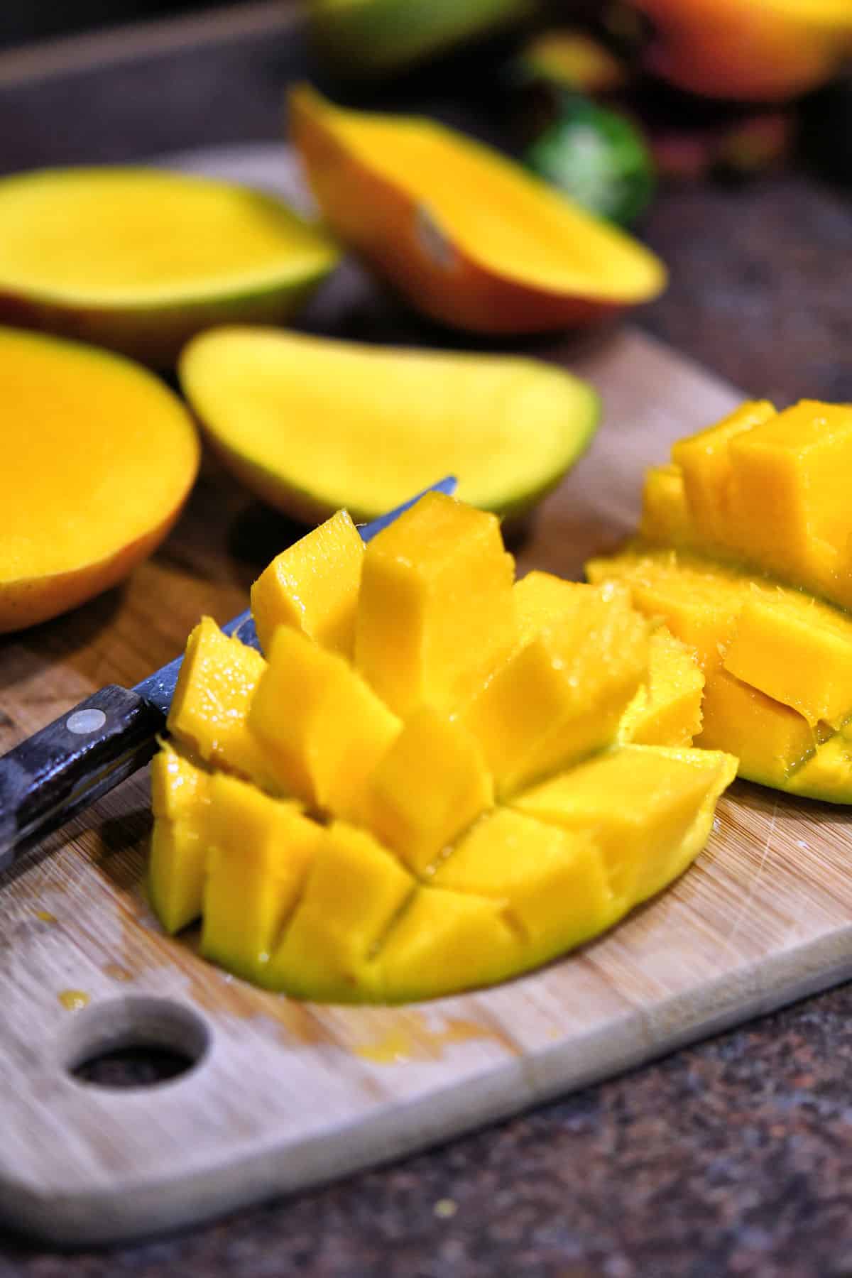 half mango on a cutting board, cubed and ready to cut individually