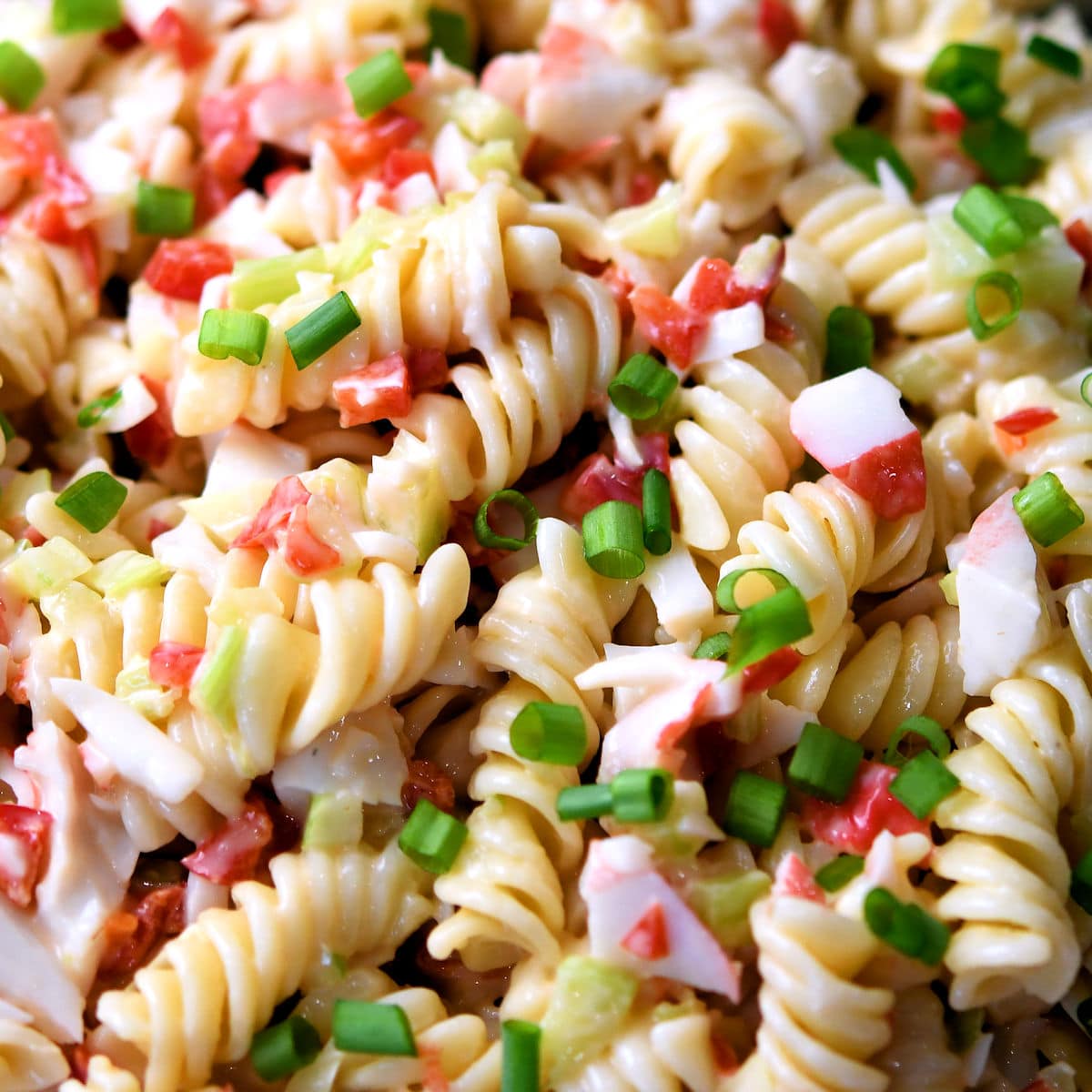 closeup of rotini pasta, imitation crab and green onion salad