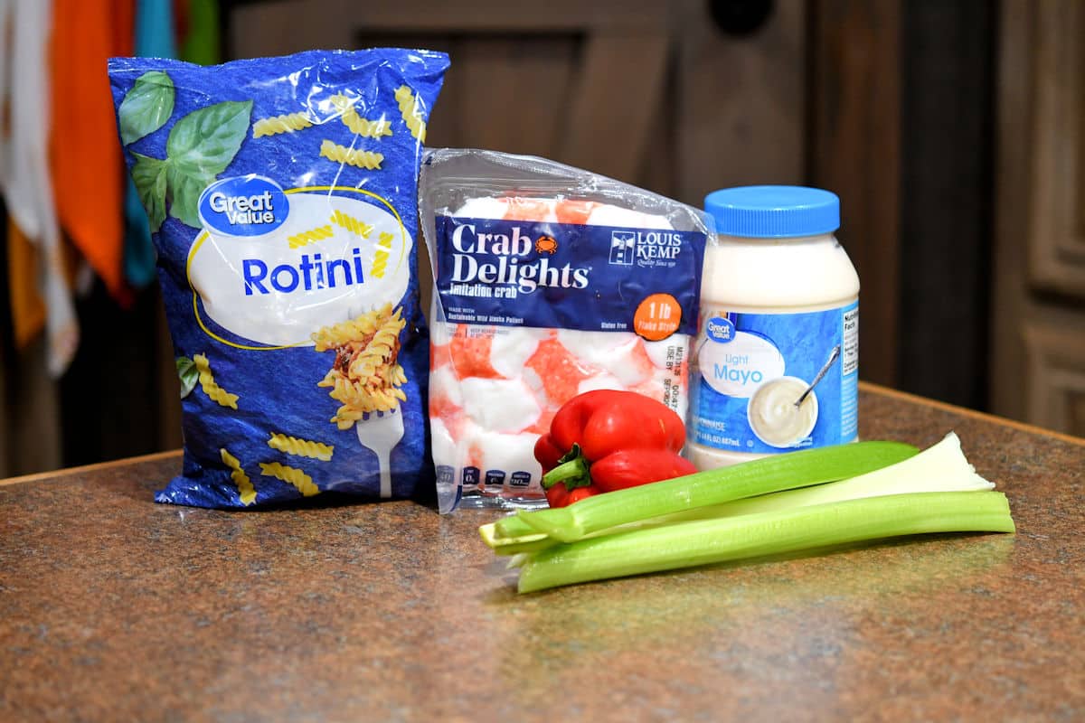 5 ingredients for crab pasta salad on a counter