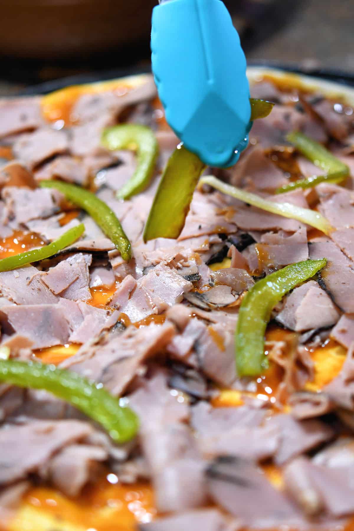 closeup of placing bell peppers on a pizza, just ready to be put in the oven