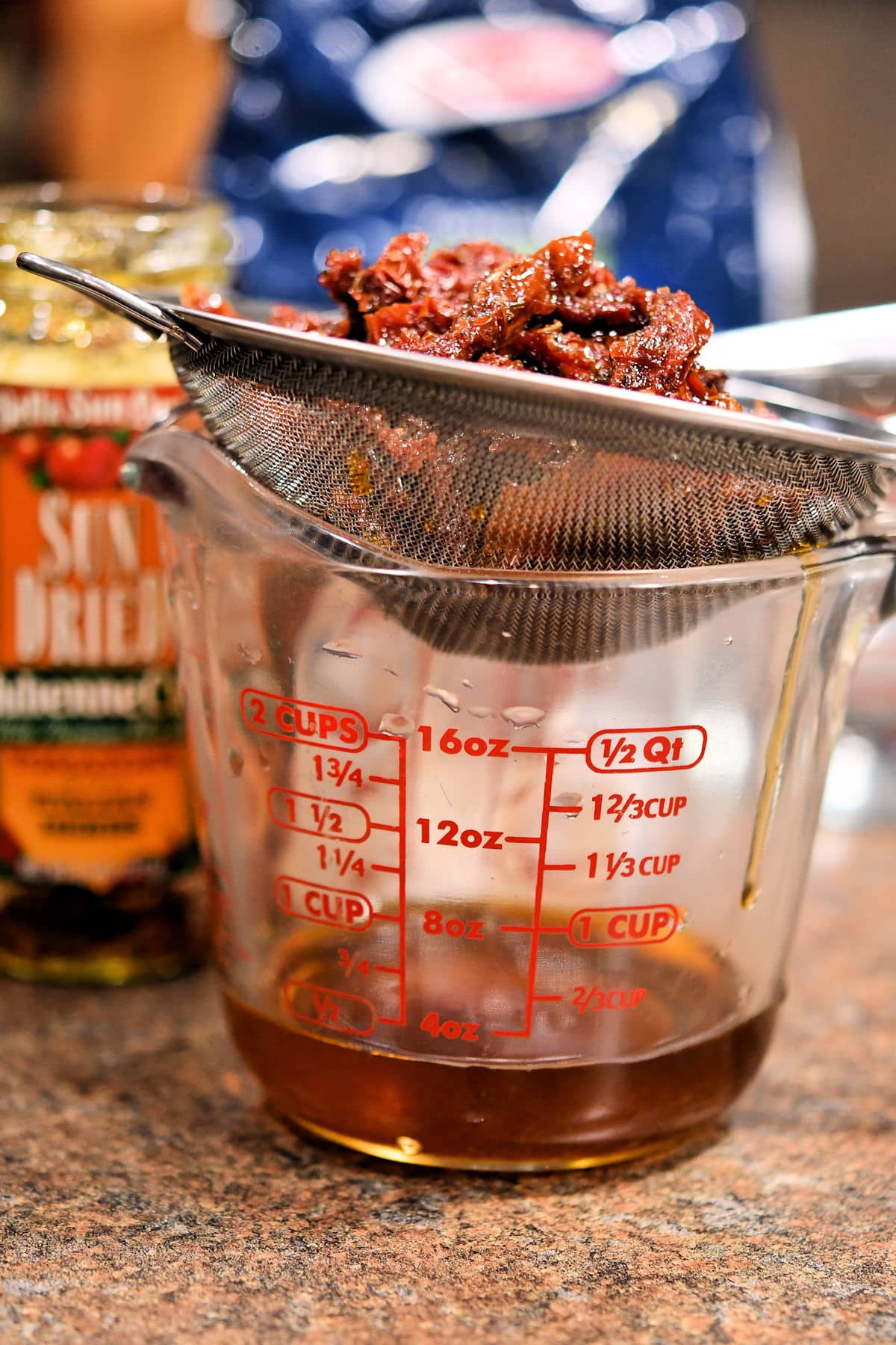 sun dried tomatoes draining into a measuring cup
