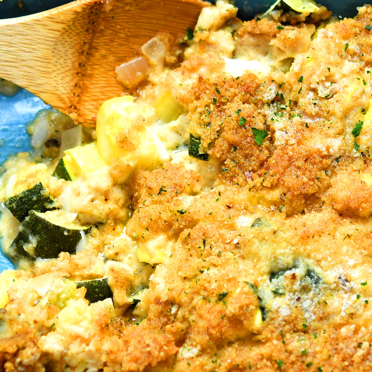 extreme closeup of zucchini casserole in a blue ceramic baking dish