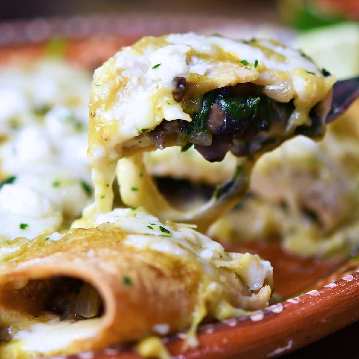 bite of spinach mushroom enchilada on a fork, ready to eat