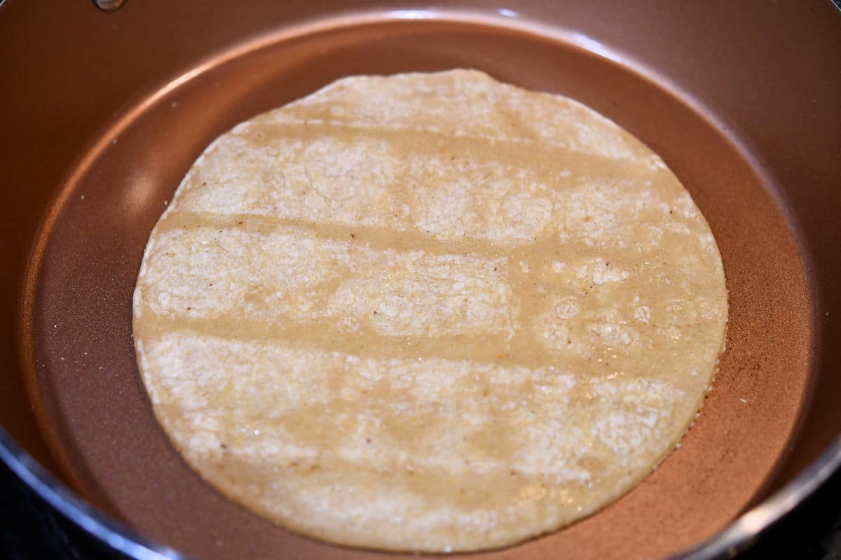 frying corn tortilla in ceramic skillet
