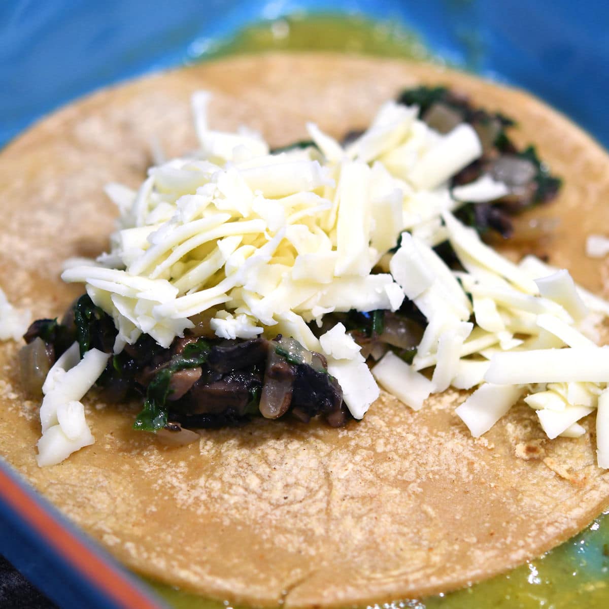 corn tortilla with spinach filling and cheese, ready to roll up
