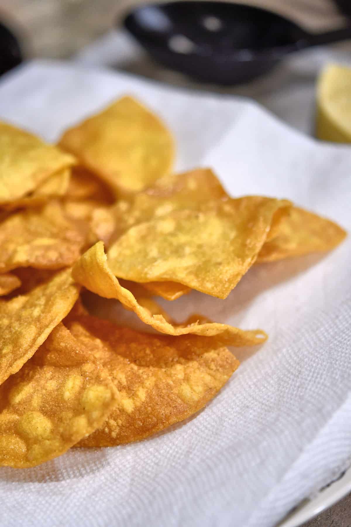 homemade fried tortilla chips drying on a paper towel