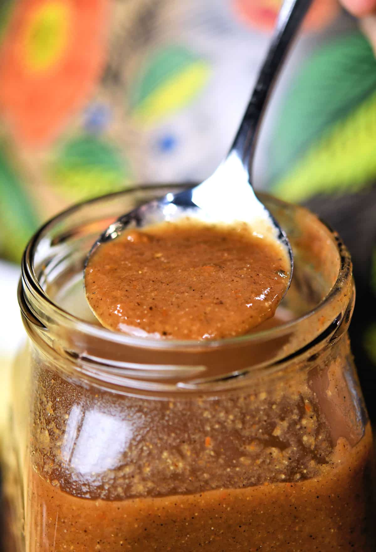 closeup of a spoonful of enchilada sauce from a glass jar