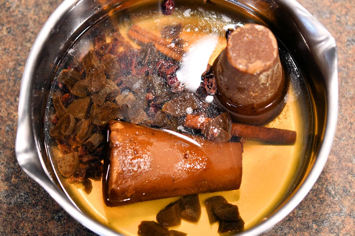 piloncillo and cinnamon sticks with water in saucepan