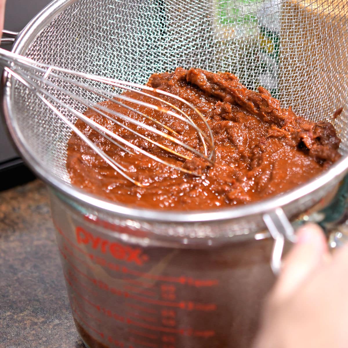 close up of straining the chiles with a whisk