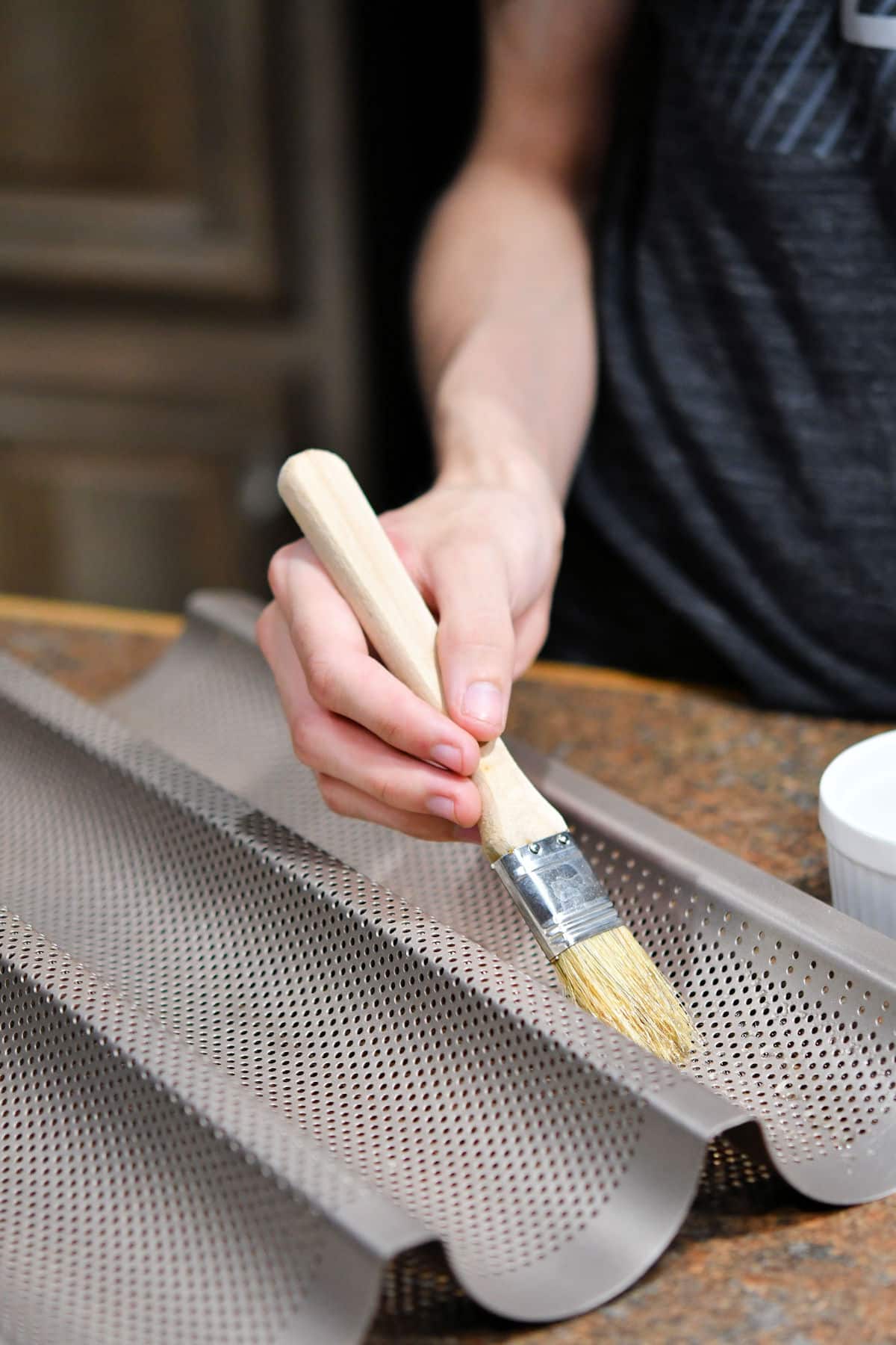 closeup of brushing oil on a baguette pan