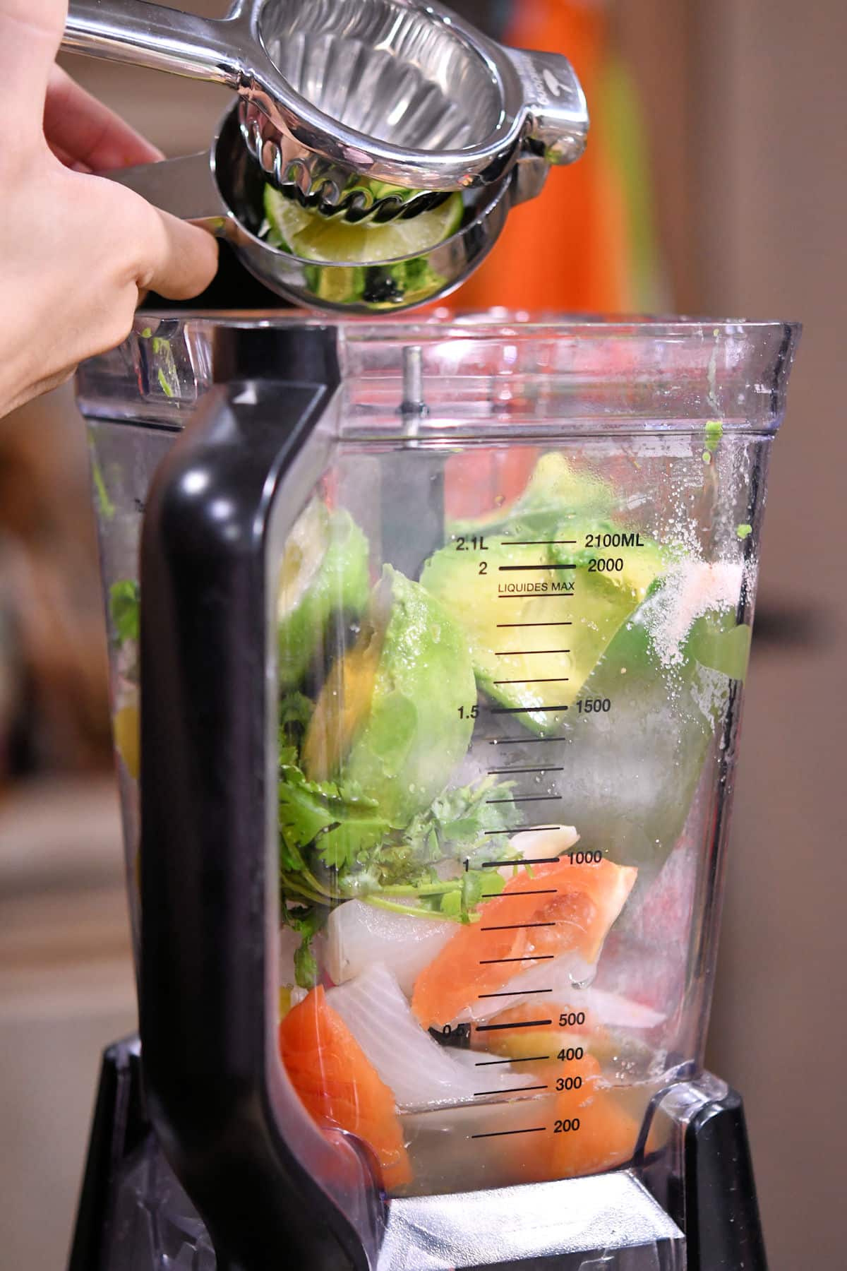 squeezing lime into a blender of avocado and other fresh vegetables