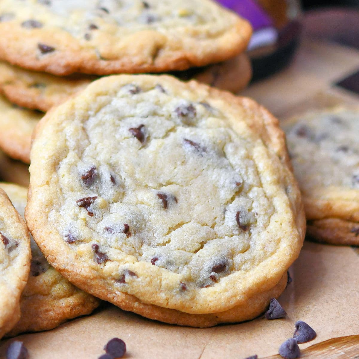 one chocolate chip cookie in focus on parchment paper