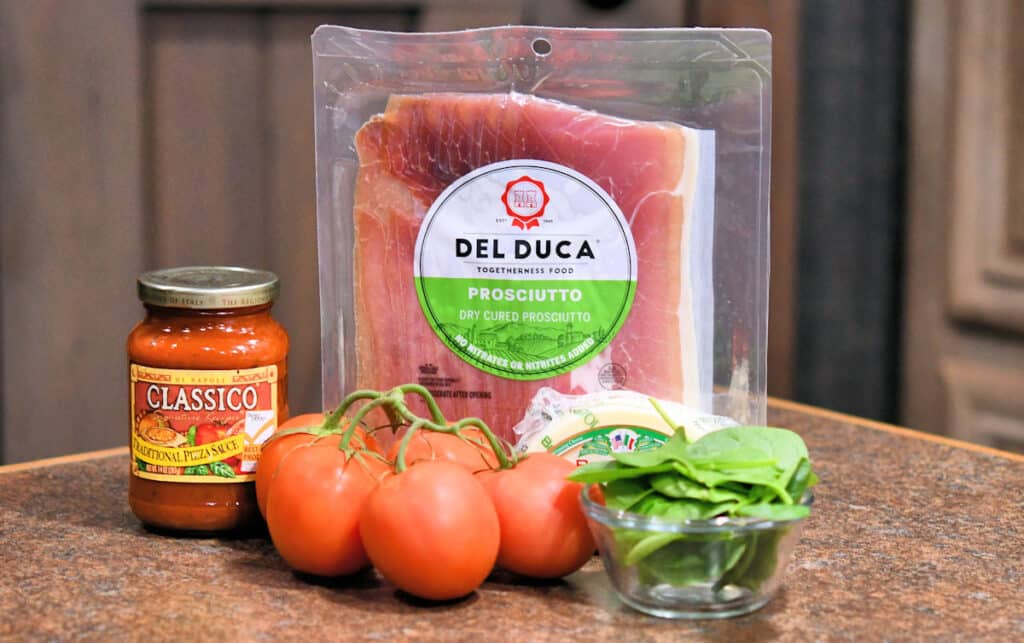 ingredients for prosciutto provolone pizza on a countertop