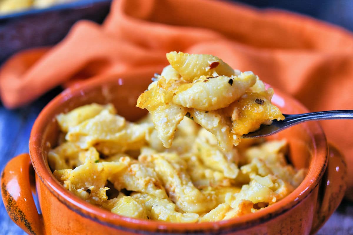 a bowl of baked macaroni and cheese with a bit on a fork above it