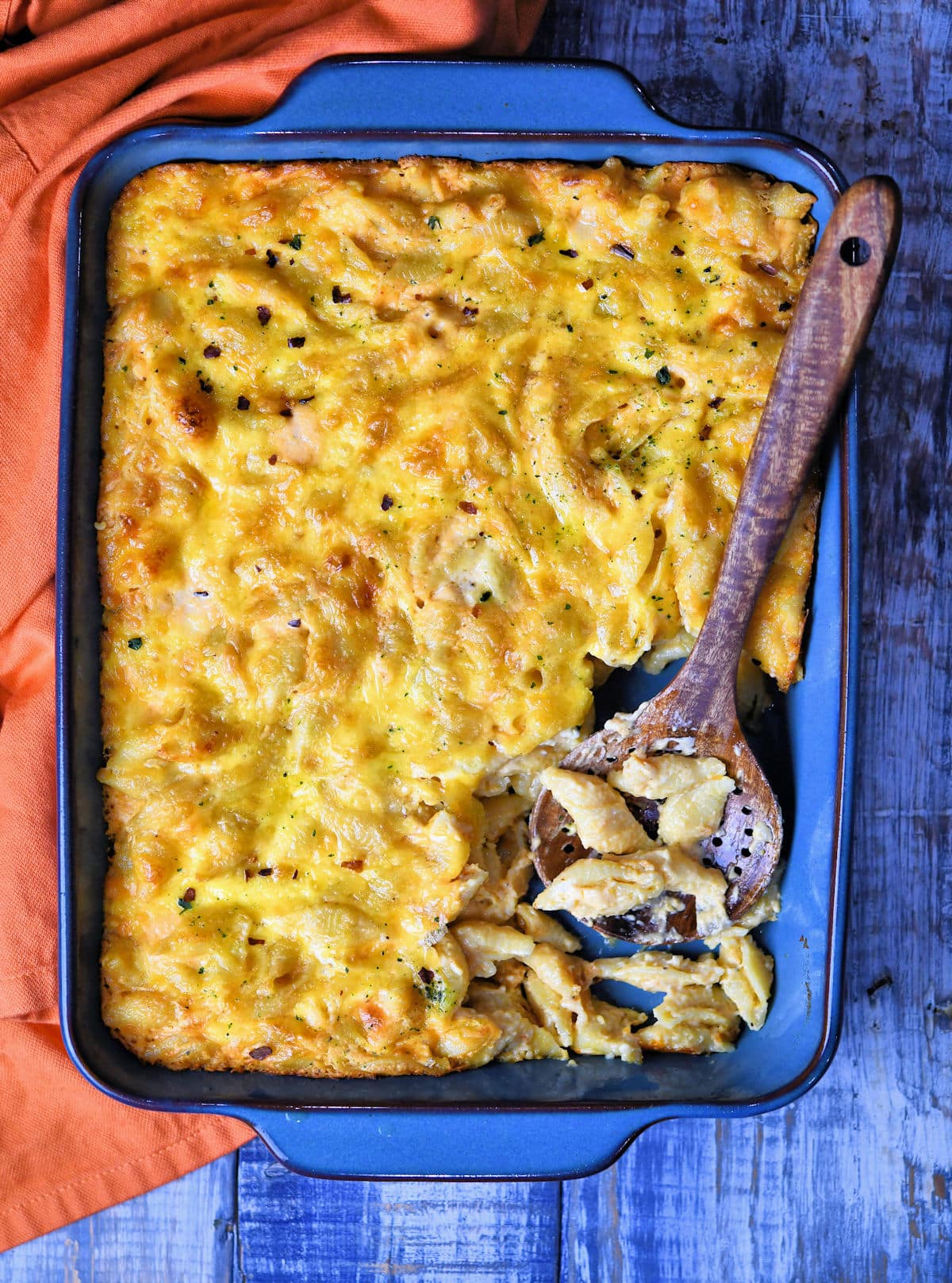 a rectangle baking dish with macaroni and cheese and an acacia wood spoon