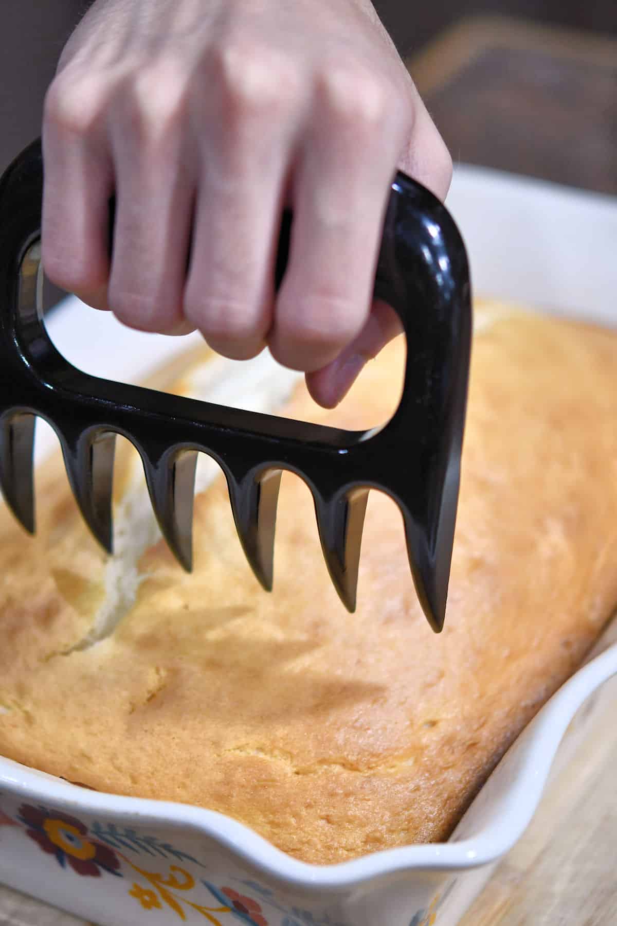 using a meat shredding claw to poke holes in a cake