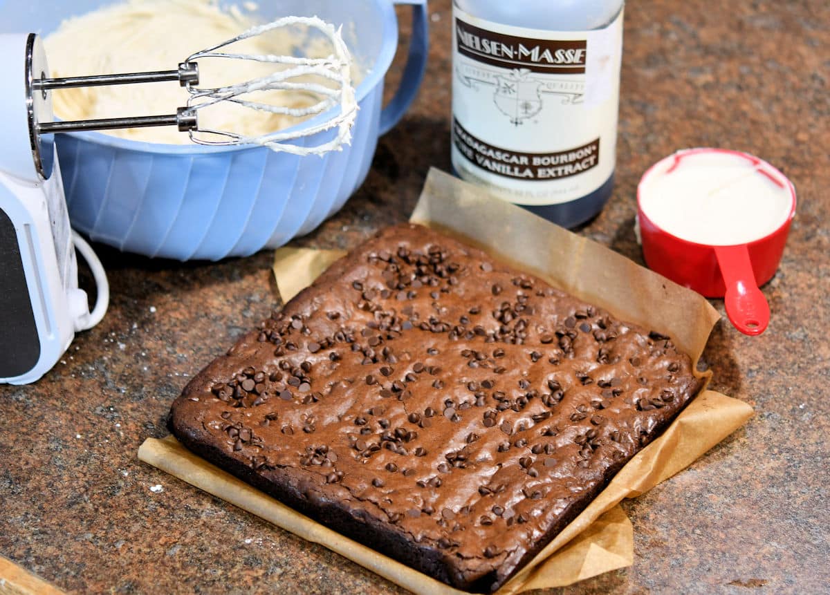 brownie base on a counter with bowl of buttercream frosting