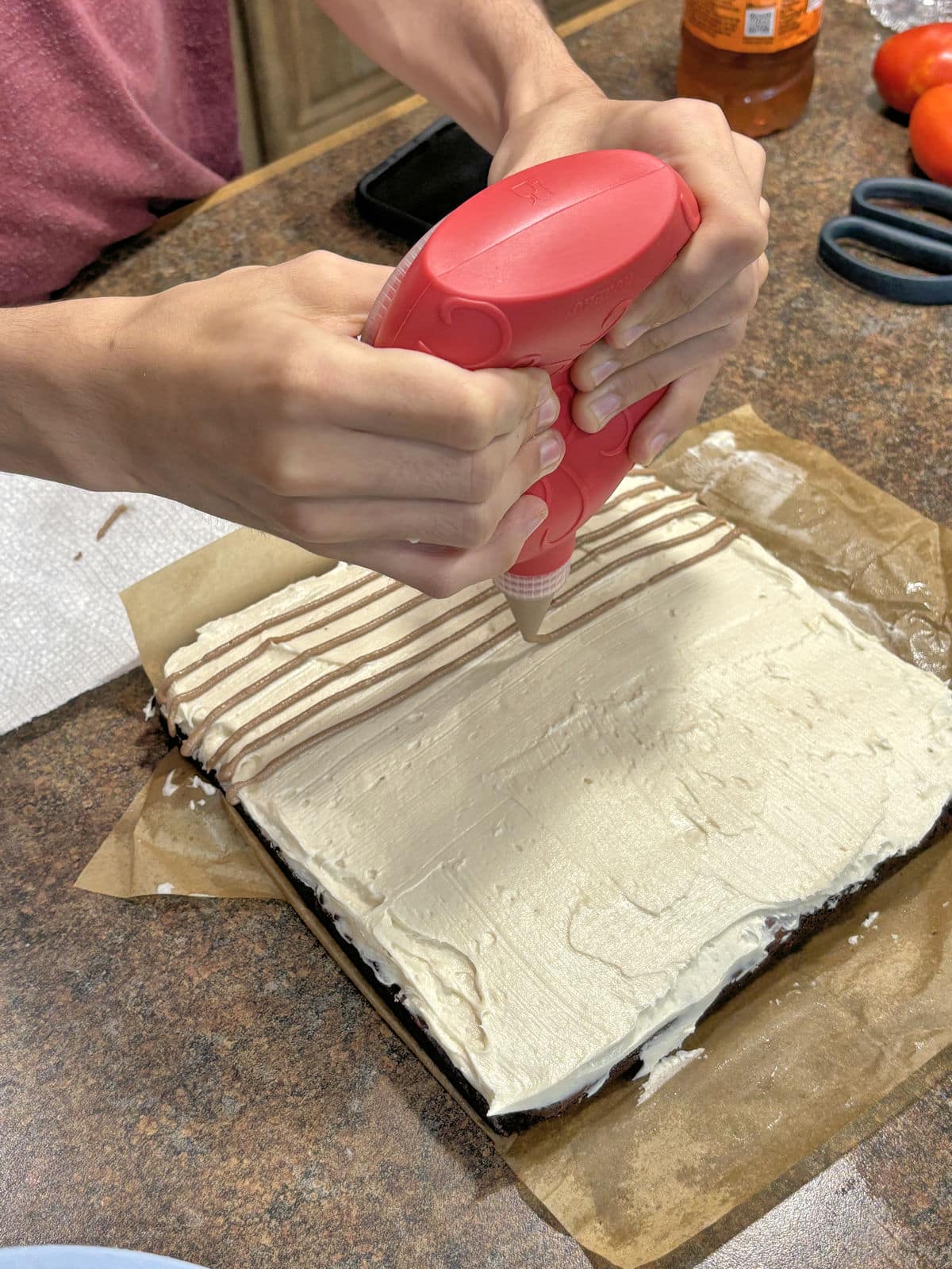 piping lines of chocolate frosting on top of buttercream base
