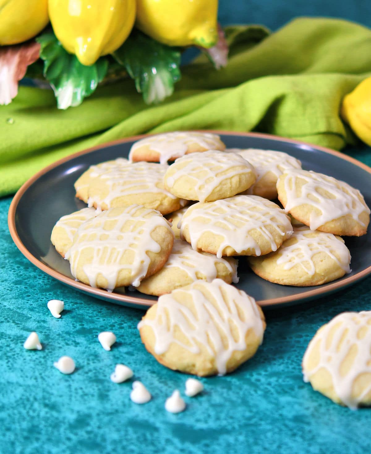 Lemon cookies on a green ceramic plate with white chocolate chips randomly placed in the front.