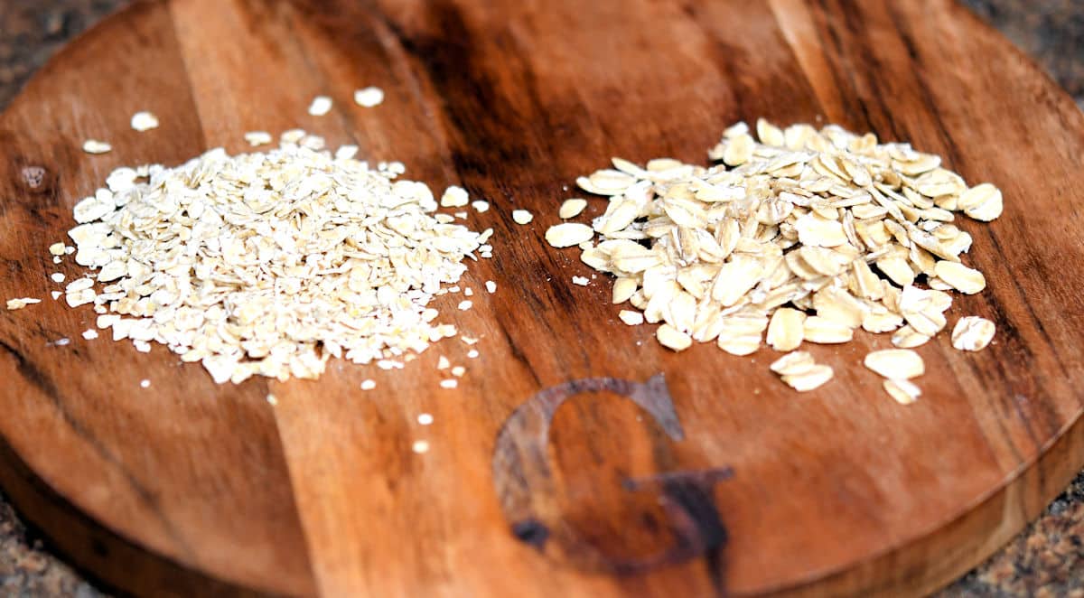comparison of old fashioned oats and quick oats on a small wooden cutting board.