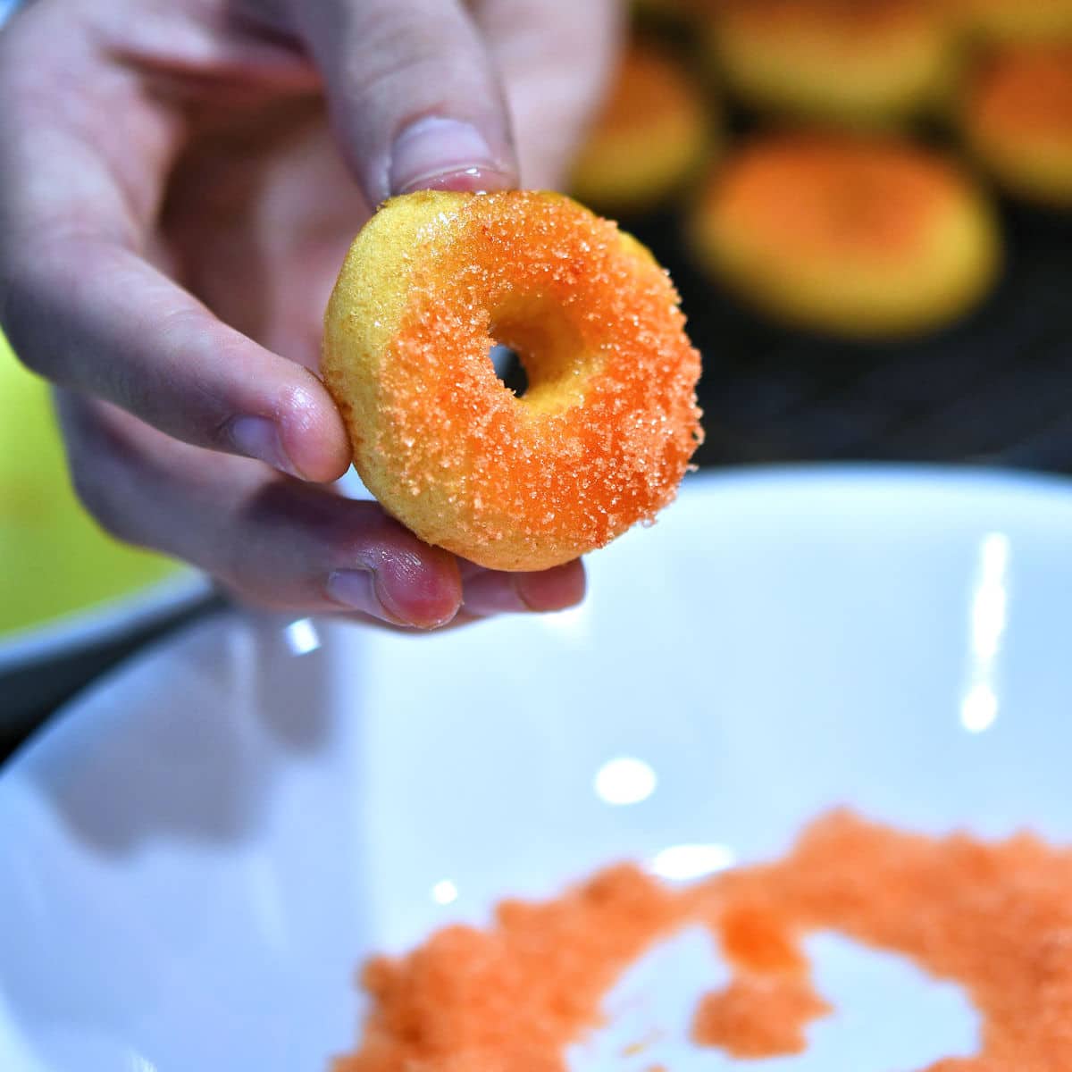 closeup of mini donut being dipped into sugar.