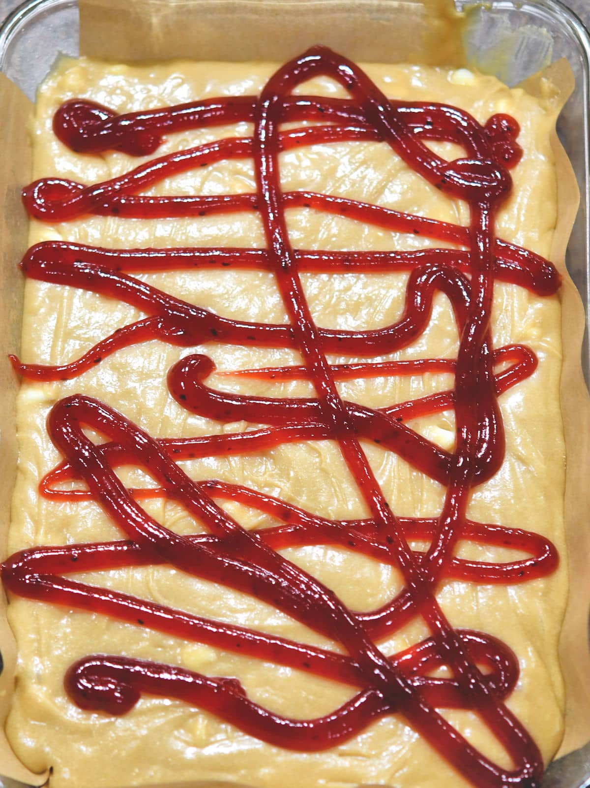 baking dish with blondie batter and raspberry filling to be swirled.