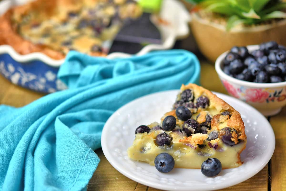 slice of blueberry clafoutis with blueberries garish on a white plate
