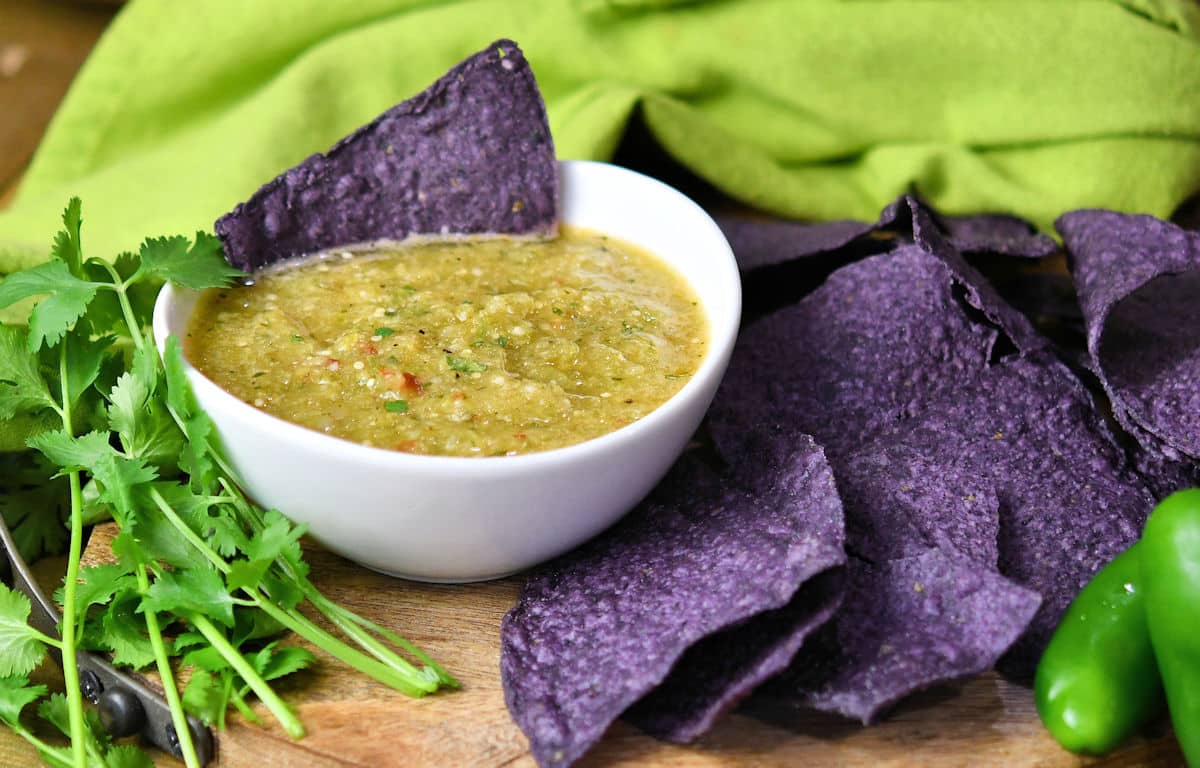 pineapple tomatillo salsa in a white bowl with blue tortilla chips