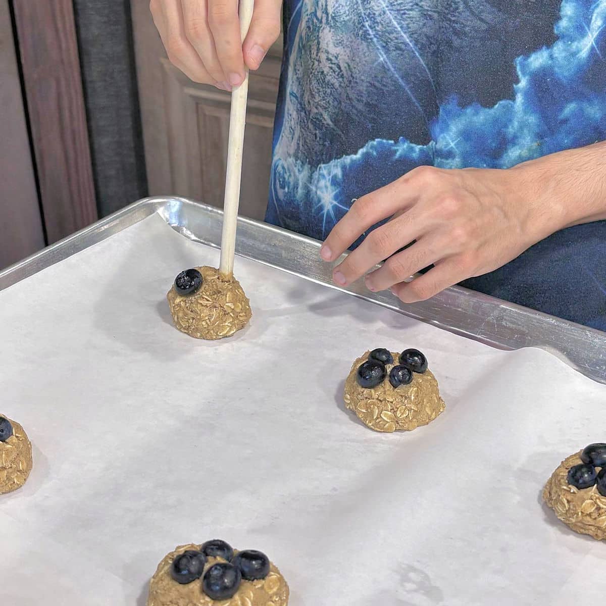 demonstration of making indentions in top of cookie dough to place blueberries on top